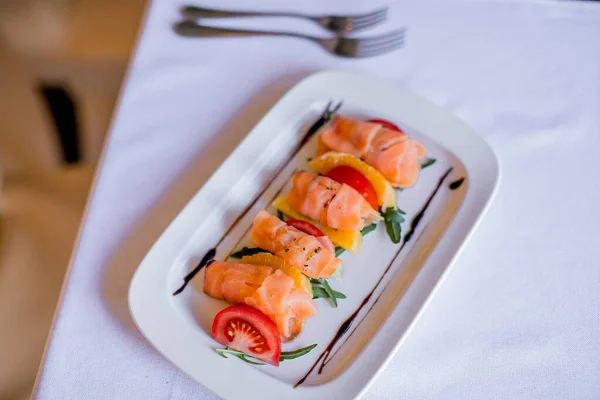 Uma porção de sushi delicioso em um prato branco na mesa Imagem De Stock