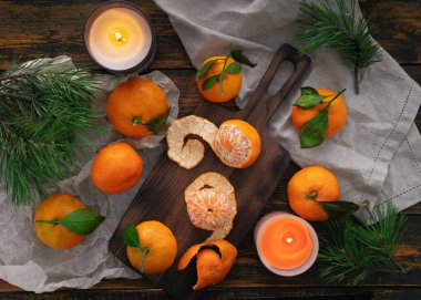 Tahta bir masanın üzerinde yaprakları olan mandallar, mumların ve çam dallarının yanında, Noel natürmortu.