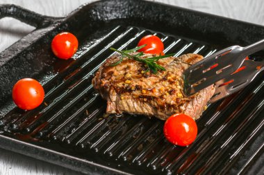 biftek tavada holding forseps ve kiraz domates