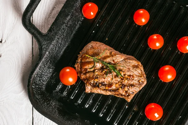 Bife segurando fórceps e tomates cereja em uma panela — Fotografia de Stock