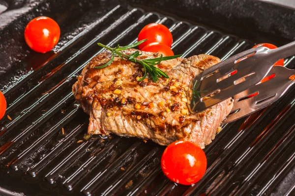 Rodajas de bistec de res en tenedor de carne y tomates cherry — Foto de Stock