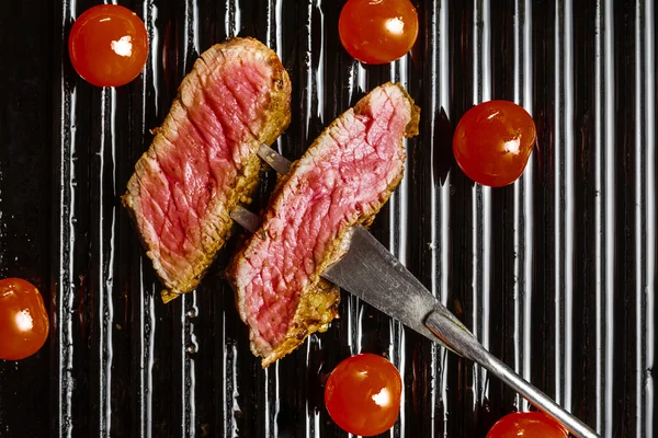 Rodajas de bistec de res en tenedor de carne y tomates cherry —  Fotos de Stock