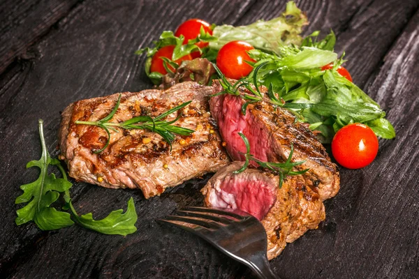 Bistecca e insalata su un tavolo di legno — Foto Stock