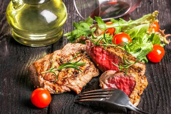 Bistecca e insalata su un tavolo di legno — Foto Stock