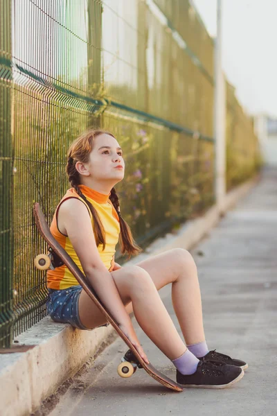 Moda çocuk kavramı - yaz aylarında kaykay olan bir tişört giyen şık küçük kız çocuk