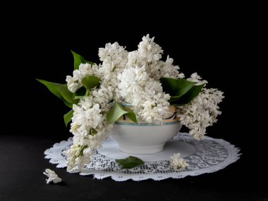 Siyah arkaplandaki beyaz leylak dalları. Masada düşmüş leylak çiçekleri.