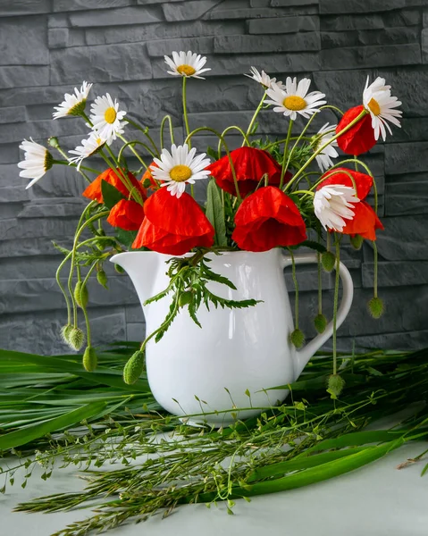 Vazoda bir buket papatya ve haşhaş.