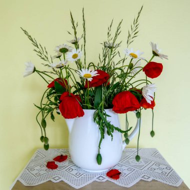Vazoda bir buket papatya ve haşhaş. 