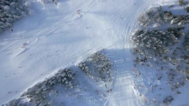 Karlı kayak pistinin tepesinde insanlar kış dağlarında kayak yapıyor ve teleferik kullanıyor. Seyahat, turizm, kış sporları, yaşam tarzı ve tatil macerası temaları için mükemmel..