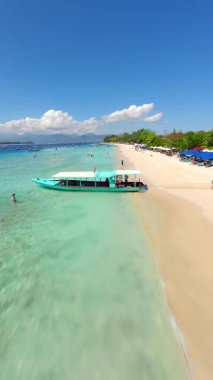 Beyaz kumsal boyunca FPV insansız hava aracı uçuşu ve Endonezya 'nın Gili Trawangan kentinin turkuaz suyu. Seyahat, macera ve tropikal doğa kavramı.