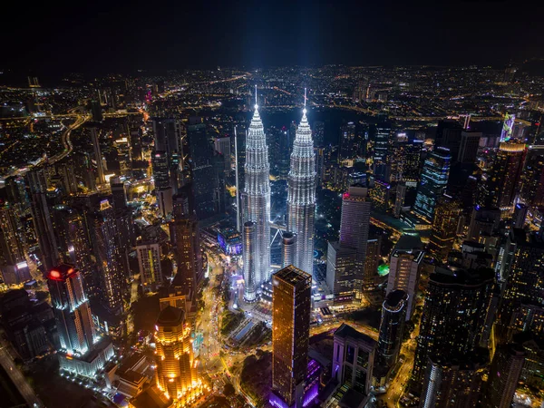 Kuala Lumpur 'un gökdelenleri aydınlanmış ve geceleri gökdelenler yükselen hava aracı görüntüsü, Malezya.