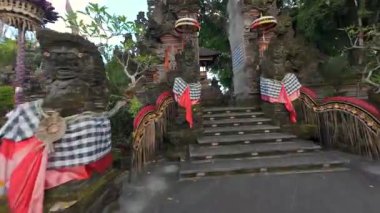 FPV İHA Bali Hindu tapınağına taş heykeller, penjor direkleri ve Endonezya 'daki kutsal kumaşlarla süslü tören kapısından girer. Ruhaniyete ve kültüre sembolik yolculuk.