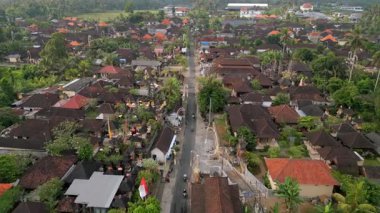 Ubud, Bali, Endonezya 'nın insansız hava aracı görüntüsü geleneksel köy evleri, yemyeşil ve yerel şehir manzarası boyunca uzanan yolları gösteriyor. Seyahat, kültür ve günlük yaşam kavramları için ideal..