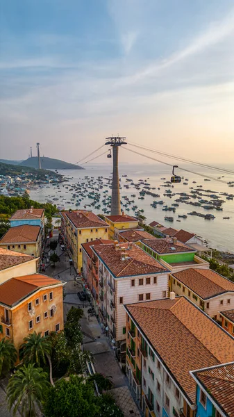 Phu Quoc Adası, Vietnam 'daki Sunset Town' ın hava manzarasında açık mavi gökyüzü altında pastel binalar, balıkçı tekneleri ve teleferik bulunuyor..