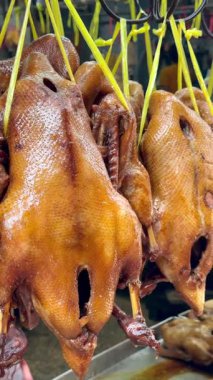 Bangkok, Tayland 'daki geleneksel Asya sokak pazarında asılı duran kızarmış ördekler. Yerel gıda ambarında popüler Çin mutfağı spesiyali sergileniyor.
