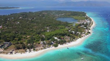 Endonezya 'daki Gili Meno adasının arka planında Gili Air ve Lombok' un görüntüsü var. Turkuaz su ve mercan resifleriyle tropik deniz manzarası.