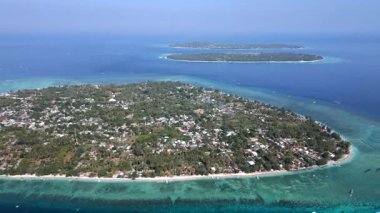 Arka planda Gili Meno ve Gili Trawangan ile Endonezya 'daki Gili Air adasının hava manzarası. Endonezya 'da turkuaz su ve mercan resifleriyle tropik deniz manzarası.