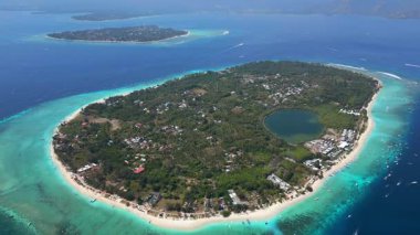 Endonezya 'daki Gili Meno adasının arka planında Gili Air ve Lombok' un görüntüsü var. Turkuaz su ve mercan resifleriyle tropik deniz manzarası.