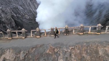 Endonezya 'daki Bromo Dağı volkan kraterinin kenarında yürüyen kadının hava görüntüsü. Doğa kavramı, seyahat, macera ve nefes kesici manzaralar..