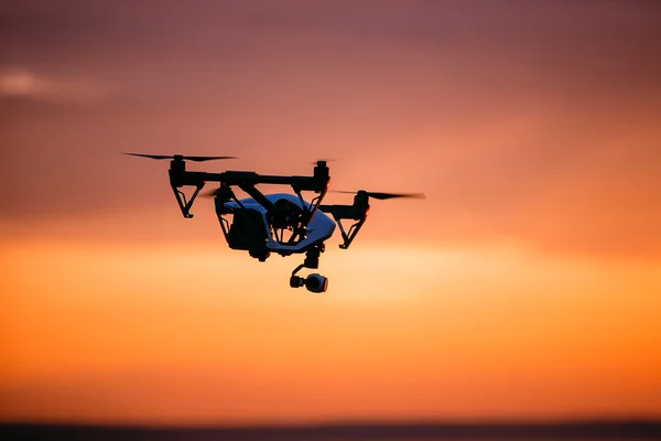 Quadrocopter drone met afstandsbediening. Donkere silhouet tegen kleurrijke zonsondergang. Soft Focus Sea.... Getinte afbeelding — Stockfoto