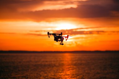 Uzaktan kumanda ile quadrocopter dron. Karanlık siluet Derma günbatımı karşı. Yumuşak odak. Tonlu görüntü