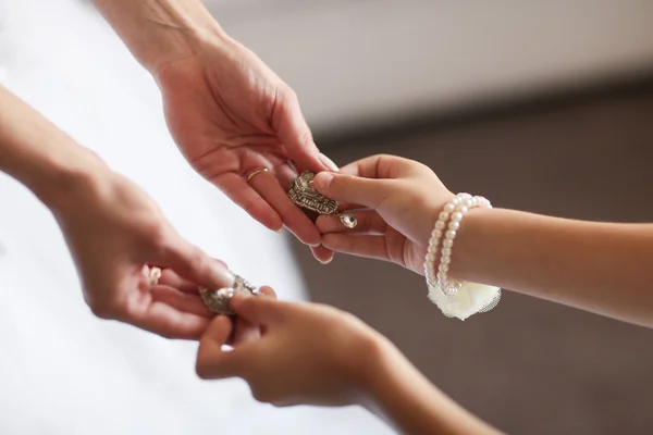 Pendientes de boda en una mano femenina, ella toma los pendientes, honorarios novia de la mañana, vestido blanco — Foto de Stock