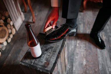 Cleaning shoes on wooden background. black shoe with a brush. Red adjustable wrench. Wedding rings. beer bottle. Wood box and firewood clipart