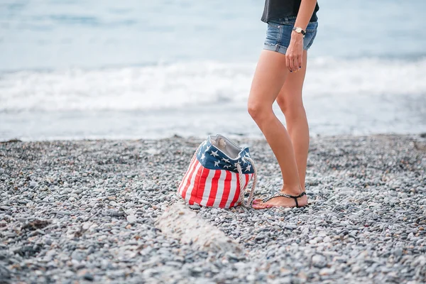 Girl stand in the beach. Usa flag bag — Stock Photo, Image