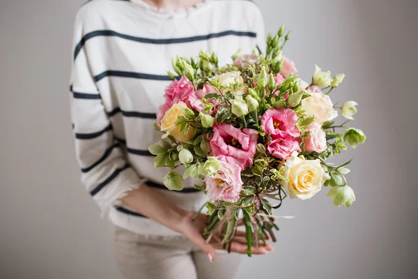 Rijke stelletje roze eustoma en rozen bloemen, groene blad in hand verse lente boeket. Zomer achtergrond. — Stockfoto