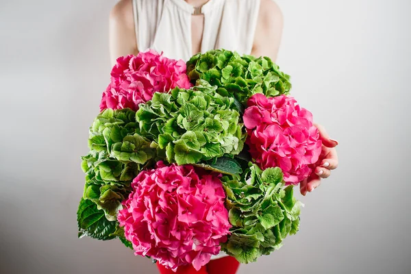 Main tenant un bouquet vert et rose couleur hortensia fond blanc. couleurs vives. nuage. 50 nuances — Photo