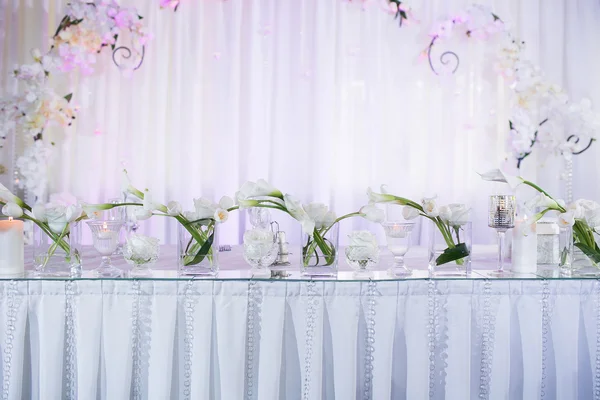Hermosa decoración de mesa interior de restaurante para boda. Flor. Nenúfares blancos y tulipanes en jarrones. Velas — Foto de Stock