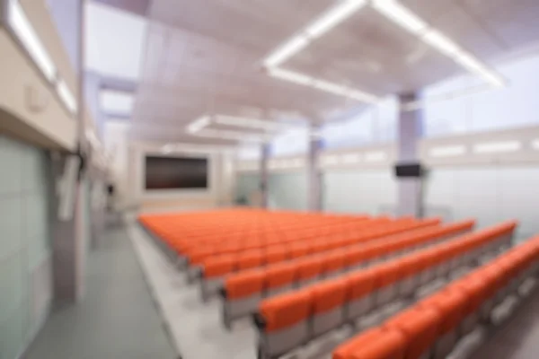 Abstract blur Rostrum with microphone and computer in conference hall. Orange color — Stock Photo, Image