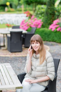 telefon görüşmesi. Beyaz akıllı telefon açık havada tatil manifatura ve gülümseyen kız mutlu güzel genç studient. Kameraya bakıyor