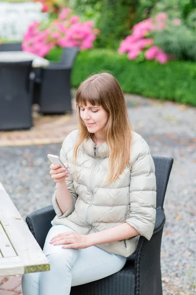 Happy beautiful young studient girl with white smart phone outdoors on holiday texting and smiling. — Stock Photo, Image