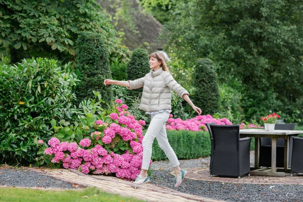 Feliz bela jovem estudante correndo e pulando no jardim europeu. Ela está olhando para a câmera — Fotografia de Stock