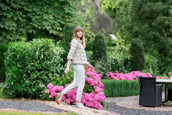 Feliz bela jovem estudante caminhando no jardim europeu. Ela está olhando para a câmera — Fotografia de Stock