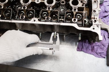 Makinist, kalınlığı kontrol etmek için bir calipher kullanarak. Tam motoru büyük onarır. Donanım banyo.