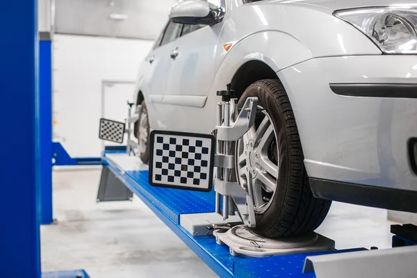 Coche en pedestal con ruedas sensores para alineamiento camber verificación en taller de estación de servicio. — Foto de Stock