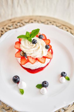 Pavlova kıtır kıtır kabuklu kremalı bir tatlıdır. Süslü çilek, nane yaprağı, yabanmersini ve krema. Lokanta, tatlı yemek.