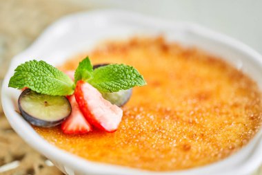 Cam kasede klasik creme brulee. İştah açıcı dondurma kapanıyor. Üzümlü ve çilekli tatlı karamel, nane ve böğürtlen süslemeli. Lokanta, tatlı yemek.