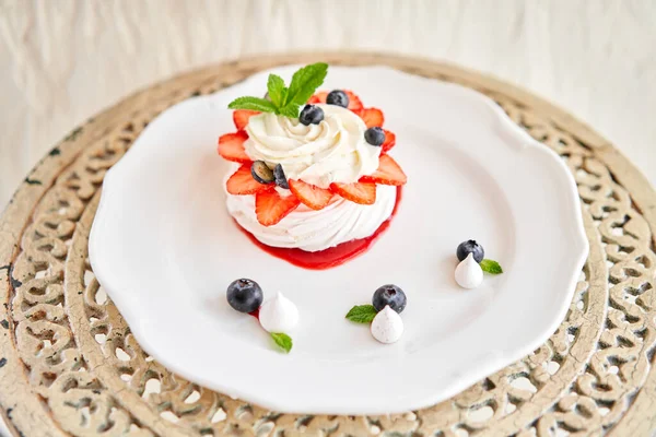 Pavlova is a meringue-based dessert with a crisp crust topped. Decorated strawberry, mint leaf, blueberry and whipped cream. Restaurant sweet food — Stock Photo, Image