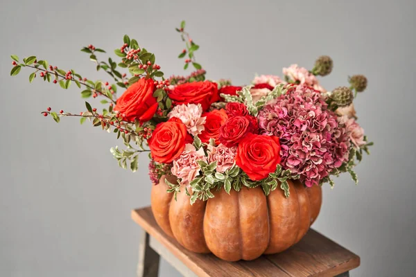 Flowers arrangement in pumpkin on wooden table. Fresh cut flowers for decoration home. European floral shop. Delivery fresh cut flower. — Stock Photo, Image