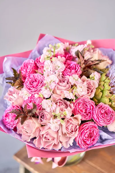 Фиолетовый и розовый букет с цветком артишока. Красивые цветы на деревянном столе. Концепция флористики. Весенние цвета. работа флориста в цветочном магазине. — стоковое фото