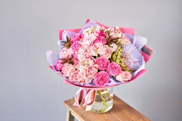 Buquê roxo e rosa com a flor da alcachofra. Lindas flores na mesa de madeira. Conceito de floricultura. Cores de primavera. o trabalho da florista em uma loja de flores. — Fotografia de Stock