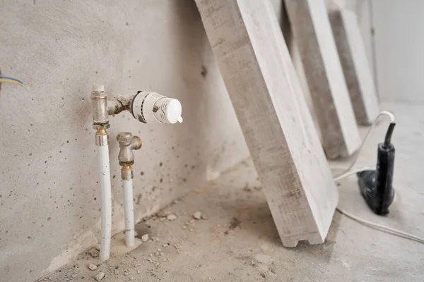Connection heating pipes to white Radiator in a new apartment under construction. Work As A Plumber, mounting water heating radiator on the white wall indoors — Stock Photo, Image