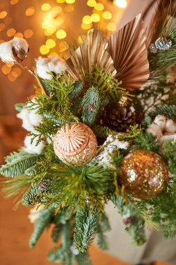 Noel çelenkleriyle süslenmiş bir çelenk ve Noel oyuncakları taşıyan genç bir kadın. Yeni yıl kutlaması. Avrupa çiçek dükkanı