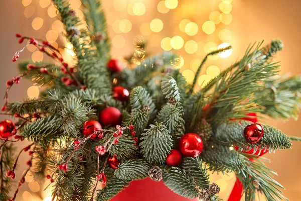 नॉर्वेजियन पाइन नॉबिलिससह ख्रिसमसची व्यवस्था आणि धातूच्या कपमध्ये ख्रिसमस सजावटसह सजवलेले. पार्श्वभूमीवर गार्लँड बोके. ख्रिसमस प्रेम. गडद लाकडी टेबल बर्फ शिंपडले — स्टॉक फोटो, इमेज