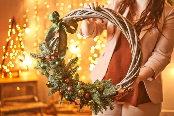 Jovem segurando um laço de grinalda de Natal decorado ramos de abeto e brinquedos de Natal para o feriado. A celebração do ano novo. Loja de flores europeia — Fotografia de Stock
