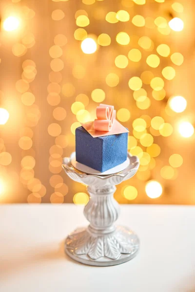 Mini dessert pâtissier en mousse avec velours bleu. guirlande lampes fond bokeh. Sous forme de coffret cadeau, rubans de chocolat. Un gâteau européen moderne. Cuisine française. Thème de Noël — Photo