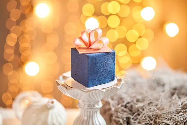 带有蓝色天鹅绒的迷你慕斯点心。石榴灯的背景。在礼品盒的形式，巧克力缎带。现代欧洲豆蛋糕。法式烹饪圣诞主题 — 图库照片